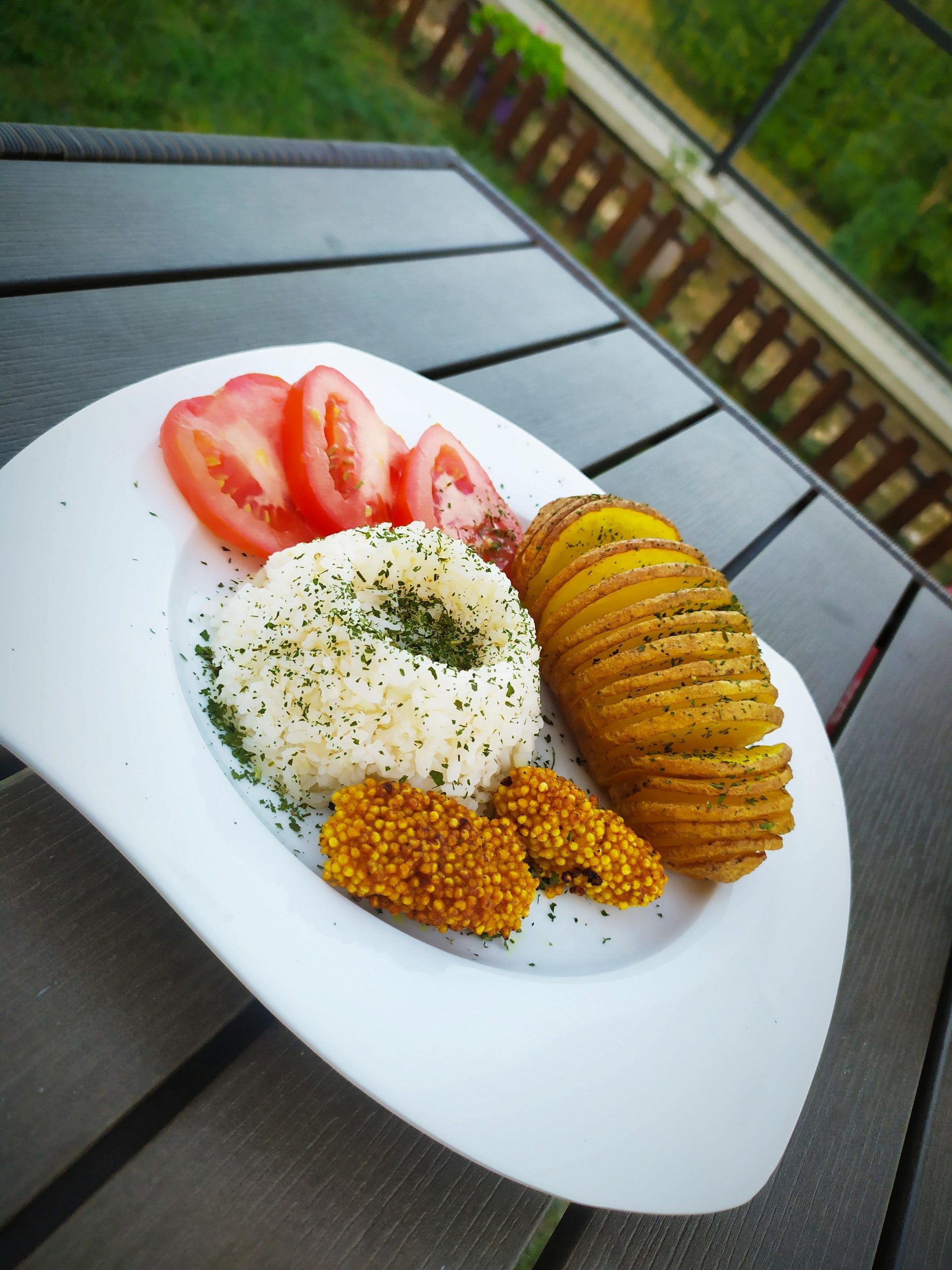Hasselback burgonya köleskolbásszal, rizzsel és paradicsommal tálalva
