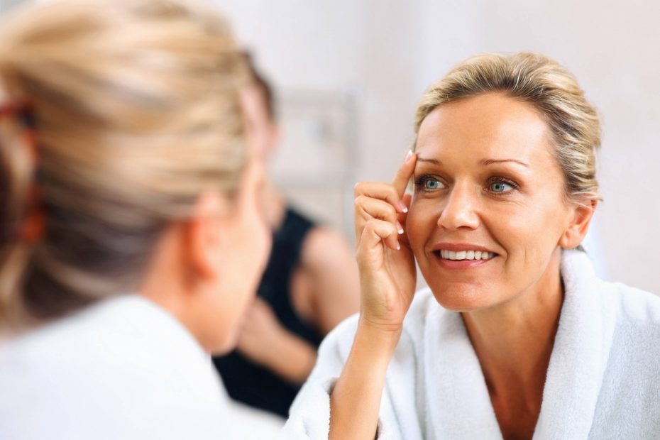 Close-up of a beautiful mature woman admiring herself in the mirror